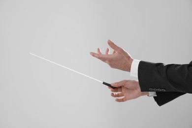 Photo of Professional conductor with baton on light grey background, closeup. Space for text