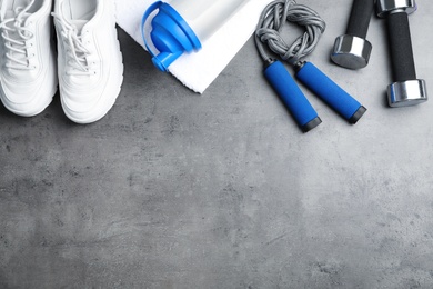 Photo of Flat lay composition with jump rope, gym equipment and space for text on grey background