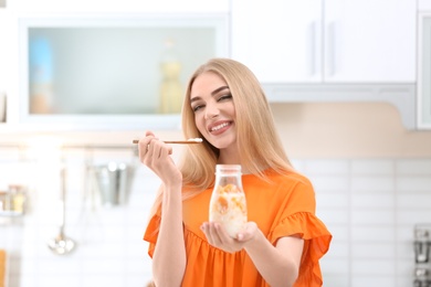 Photo of Young woman with yogurt in kitchen