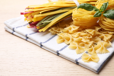 Different types of pasta on wooden table, closeup