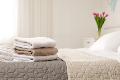 Soft bath towels on bed in hotel suite, space for text