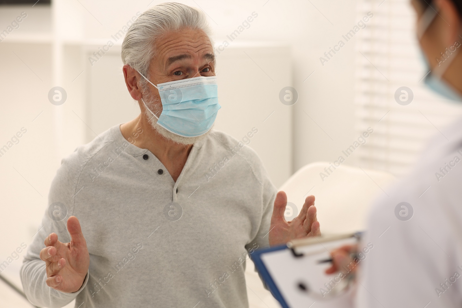 Photo of Elderly patient wearing protective mask and nurse in hospital