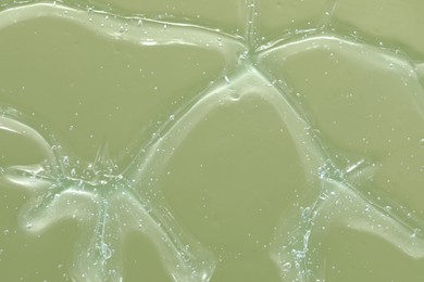 Photo of Transparent cleansing gel on green background, closeup. Cosmetic product