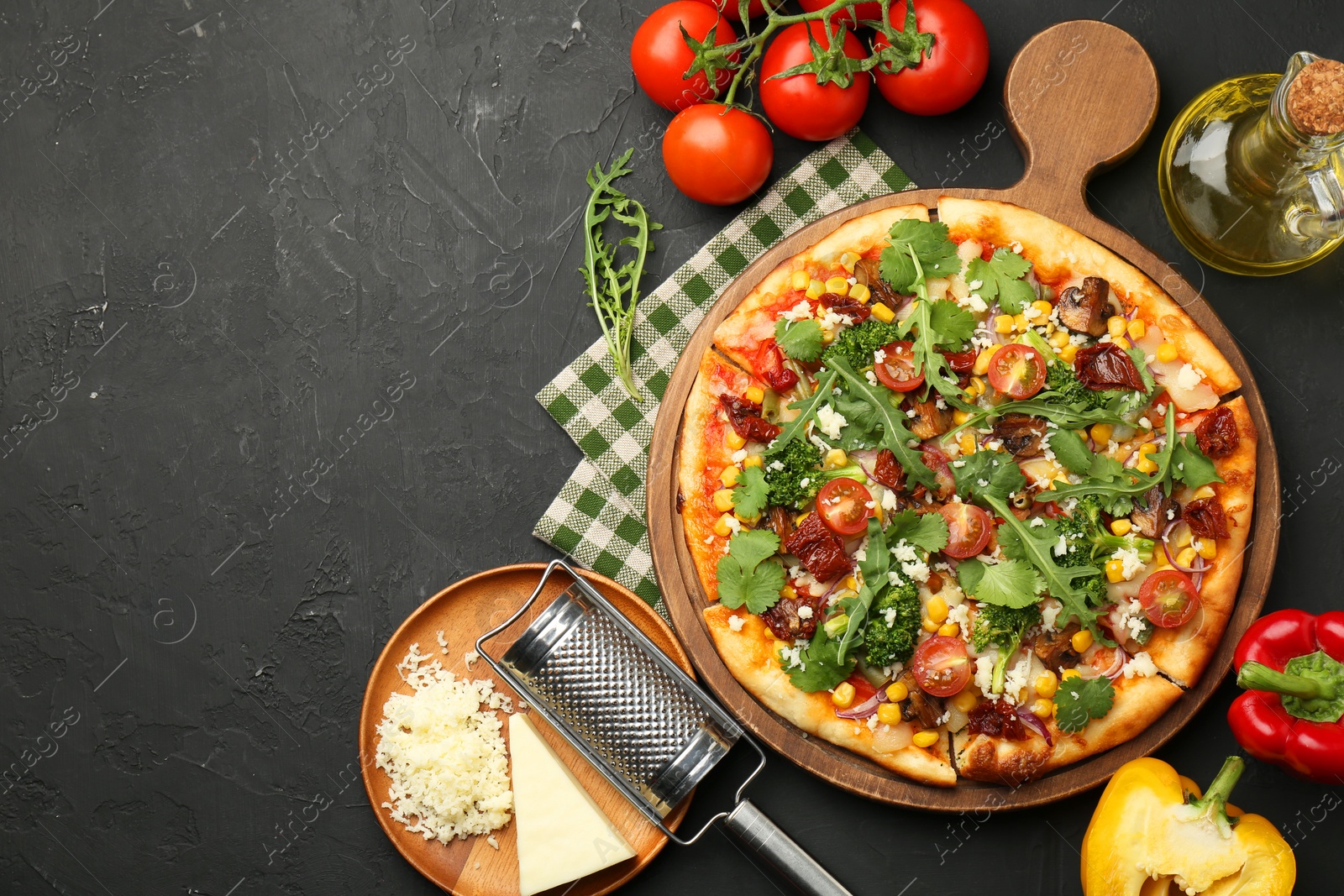 Photo of Delicious vegetarian pizza, ingredients and grater on black table, flat lay. Space for text