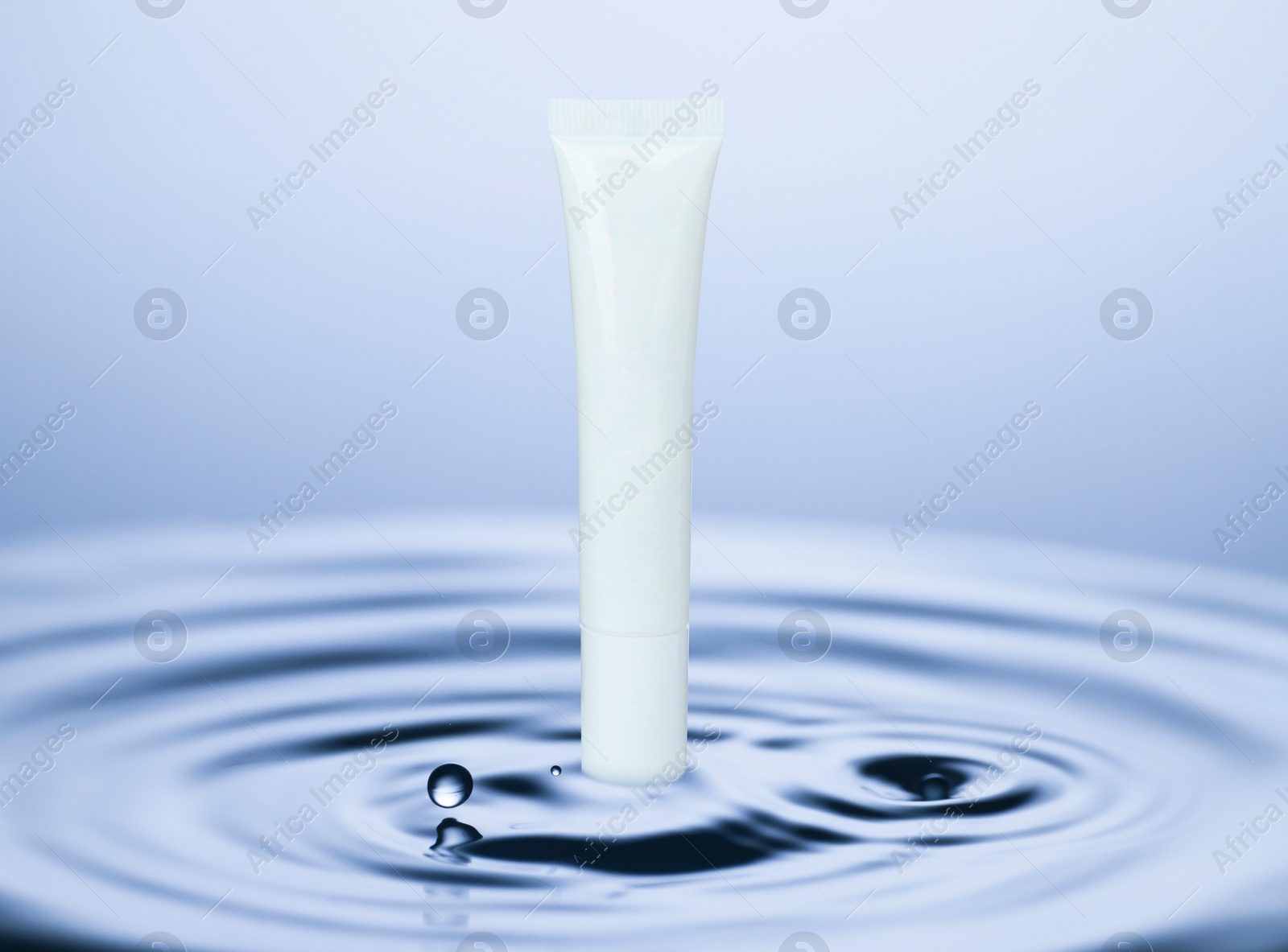 Image of Tube of cosmetic product and rippled water on light blue background. Space for design