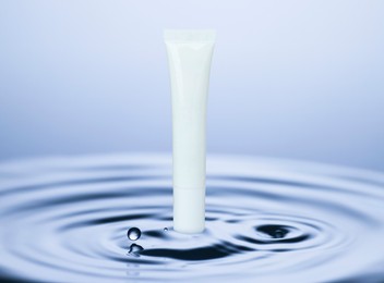 Image of Tube of cosmetic product and rippled water on light blue background. Space for design