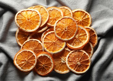 Many dry orange slices on grey cloth, flat lay