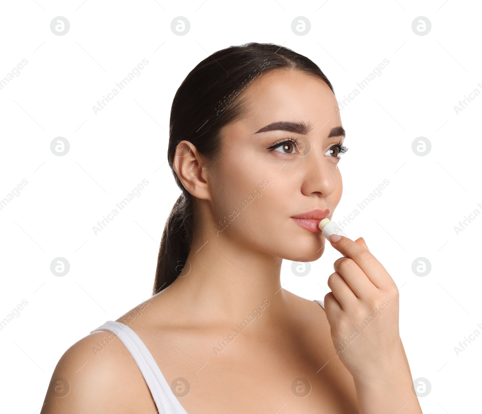 Photo of Young woman applying lip balm on white background