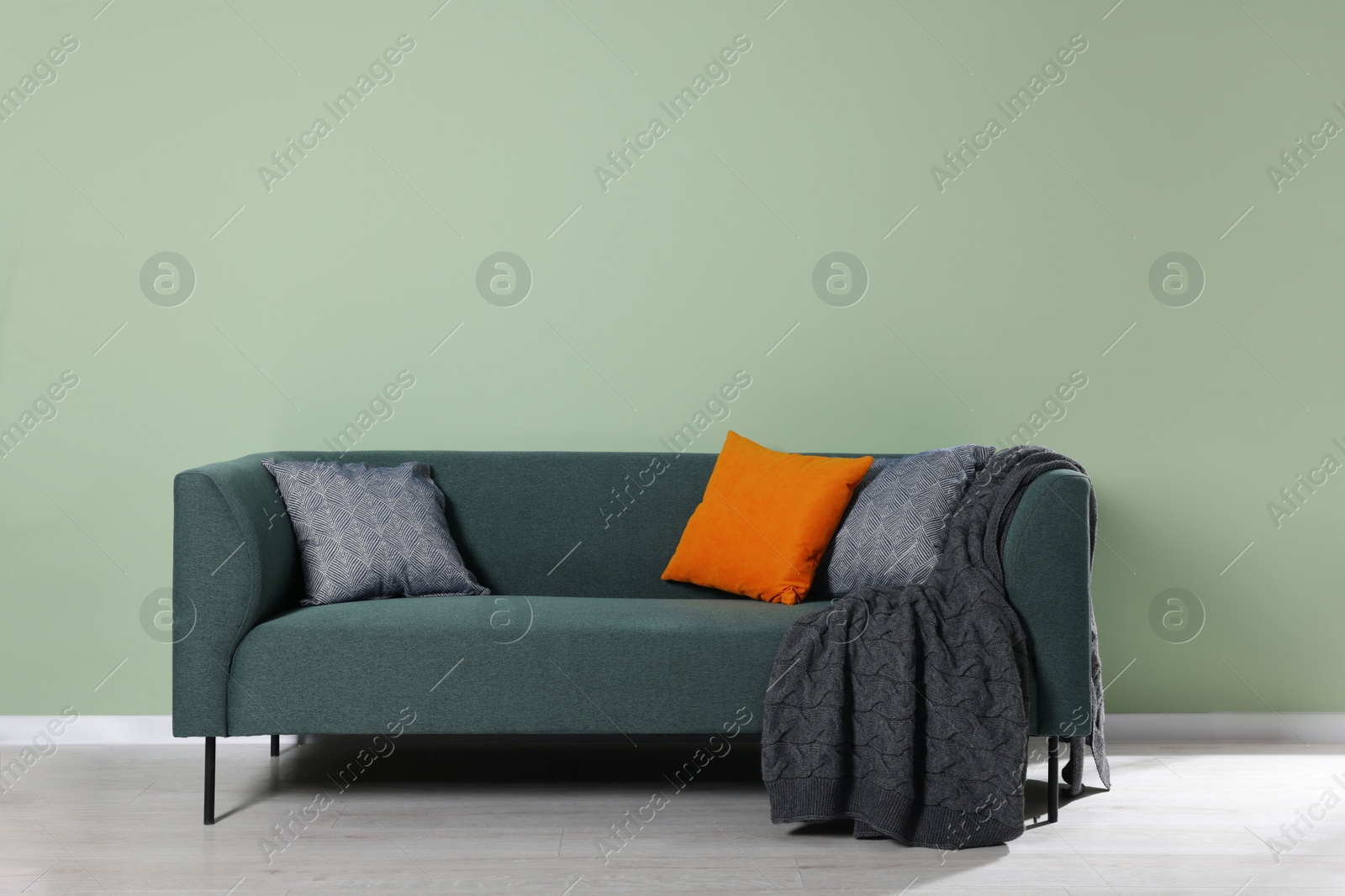 Photo of Comfortable sofa with decorative cushions and blanket indoors