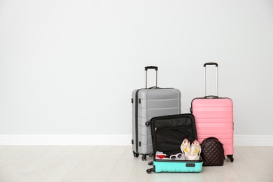 Photo of Modern suitcases on floor near light wall. Space for text