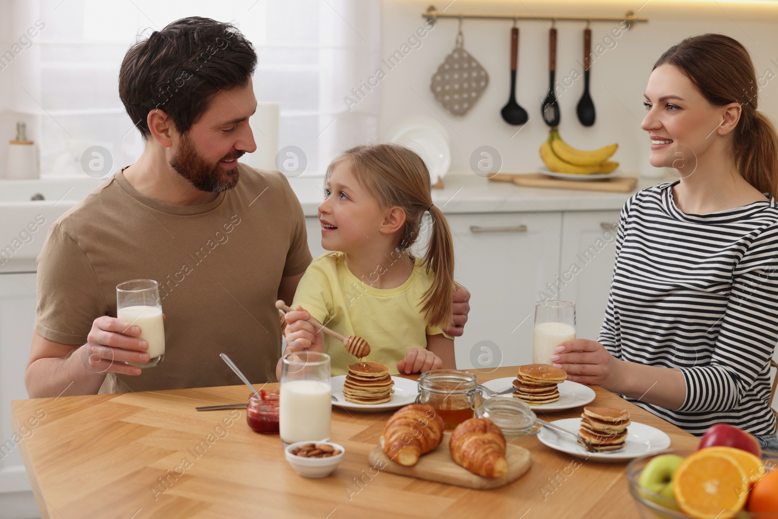 Photo of Happy family having breakfast at table in kitchen