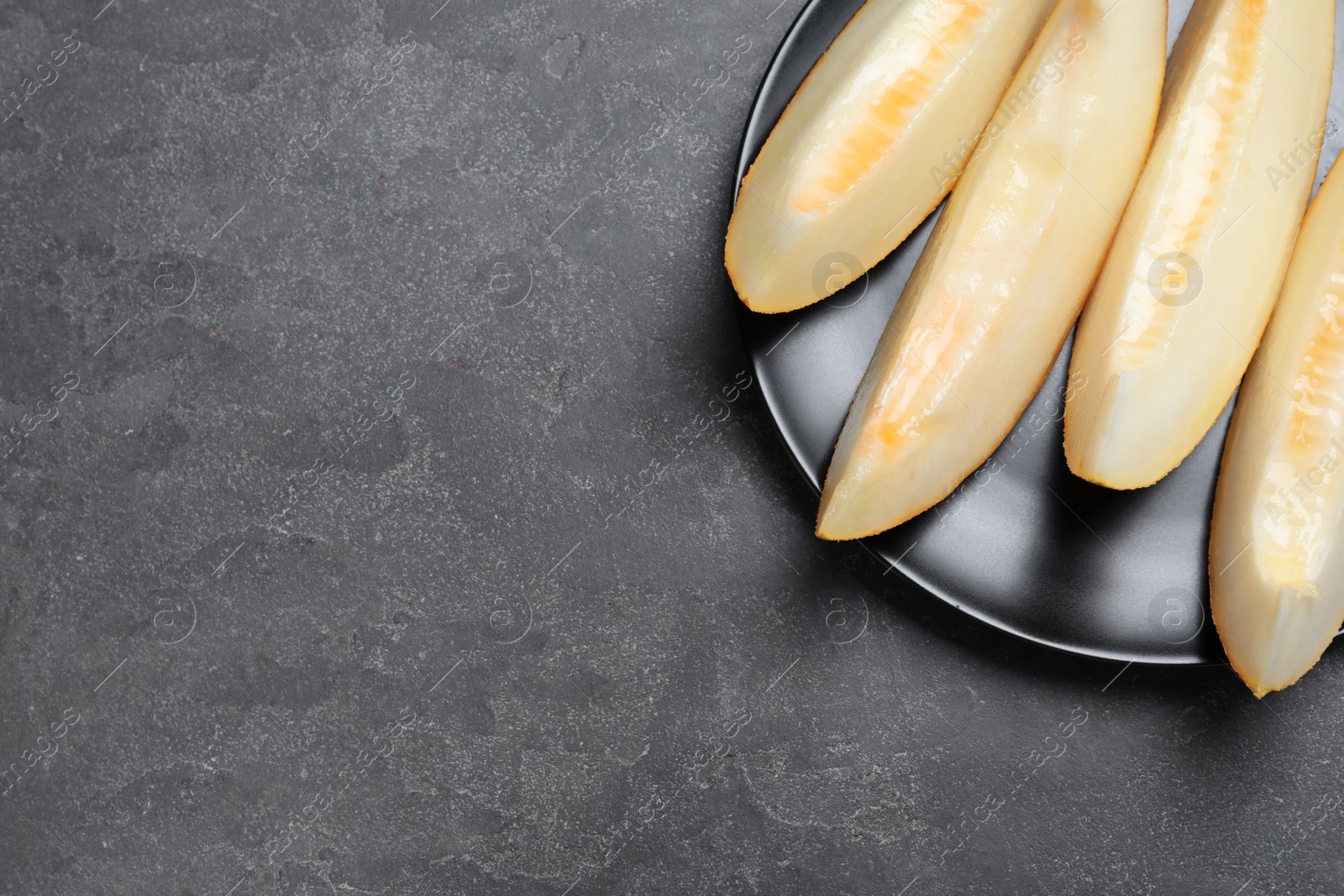 Photo of Slices of delicious honey melon on black table, top view. Space for text