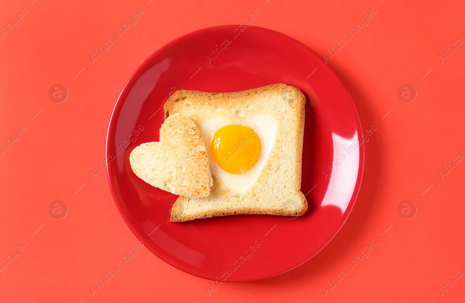 Photo of Tasty toast with fried egg on coral background, top view