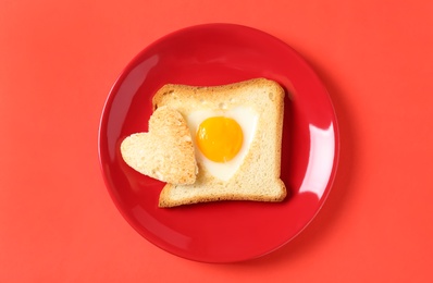 Tasty toast with fried egg on coral background, top view