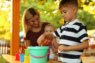 Nanny and cute children playing with toys outdoors