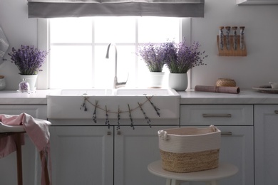 Beautiful lavender flowers on countertop near sink in stylish kitchen interior