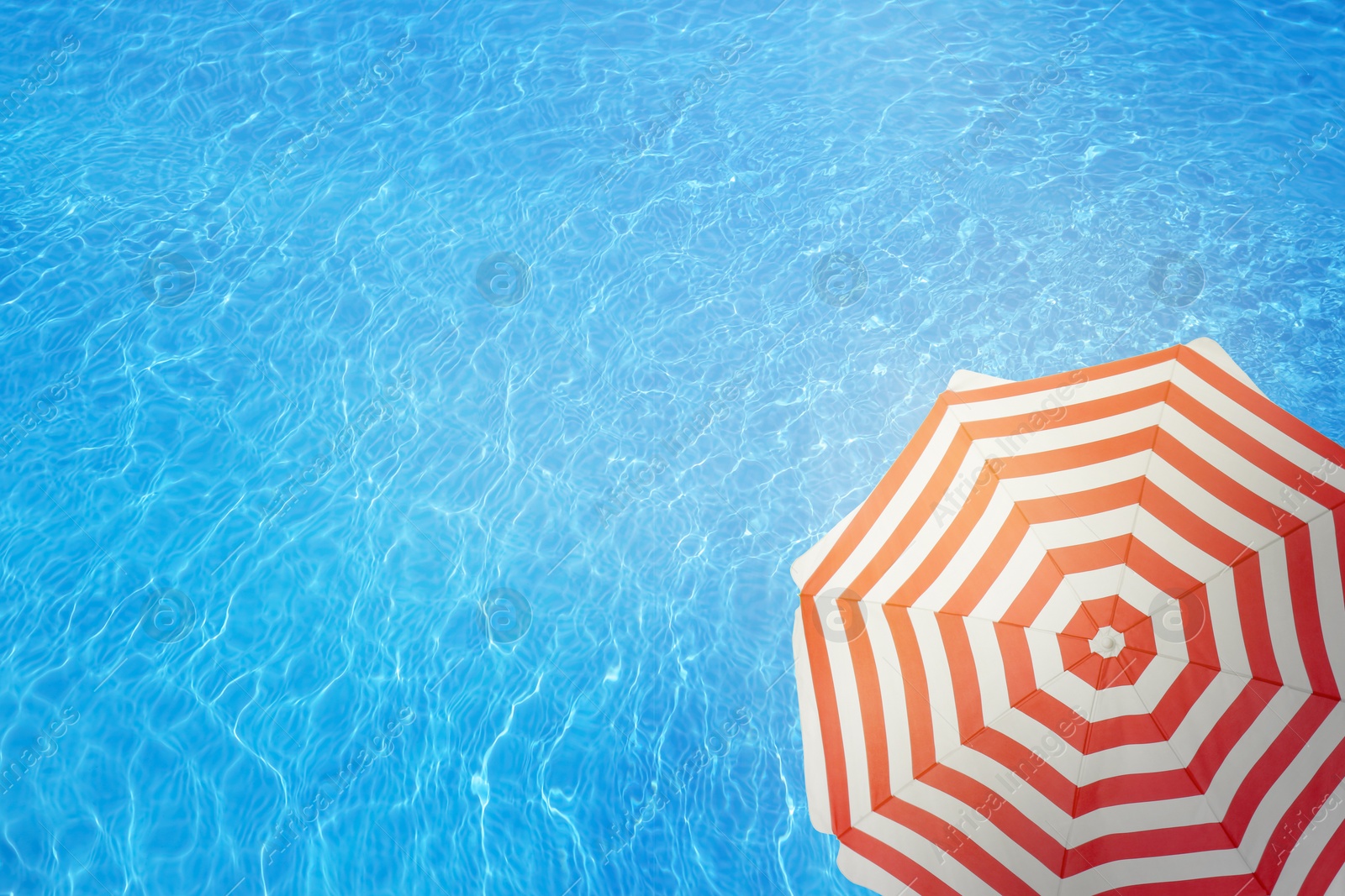 Image of Open beach umbrella and swimming pool. Summer vacation