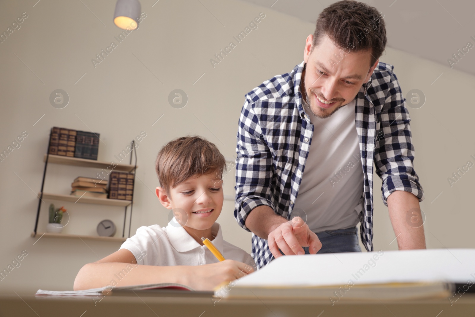 Photo of Dad helping his son with school assignment at home