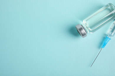 Photo of Vial and syringe on turquoise background, flat lay with space for text. Vaccination and immunization