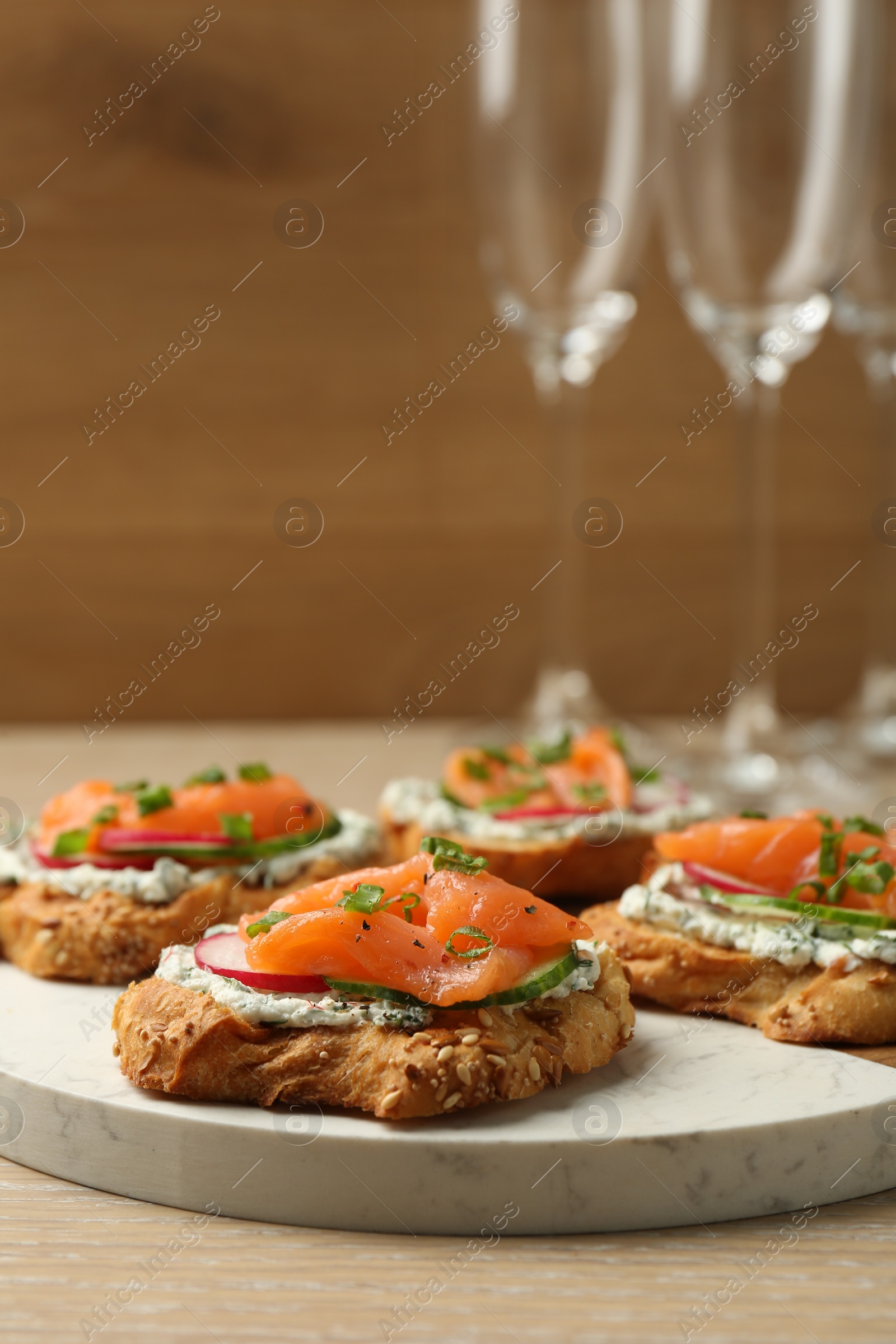 Photo of Tasty canapes with salmon, cucumber, radish and cream cheese on wooden table