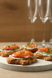 Photo of Tasty canapes with salmon, cucumber, radish and cream cheese on wooden table