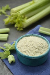 Photo of Natural celery powder in bowl and fresh stalks on grey table