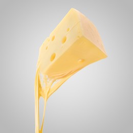 Tasty cheese stretching in air on grey background