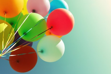 Image of Colorful balloons flying in blue sky on sunny day, low angle view. Space for text