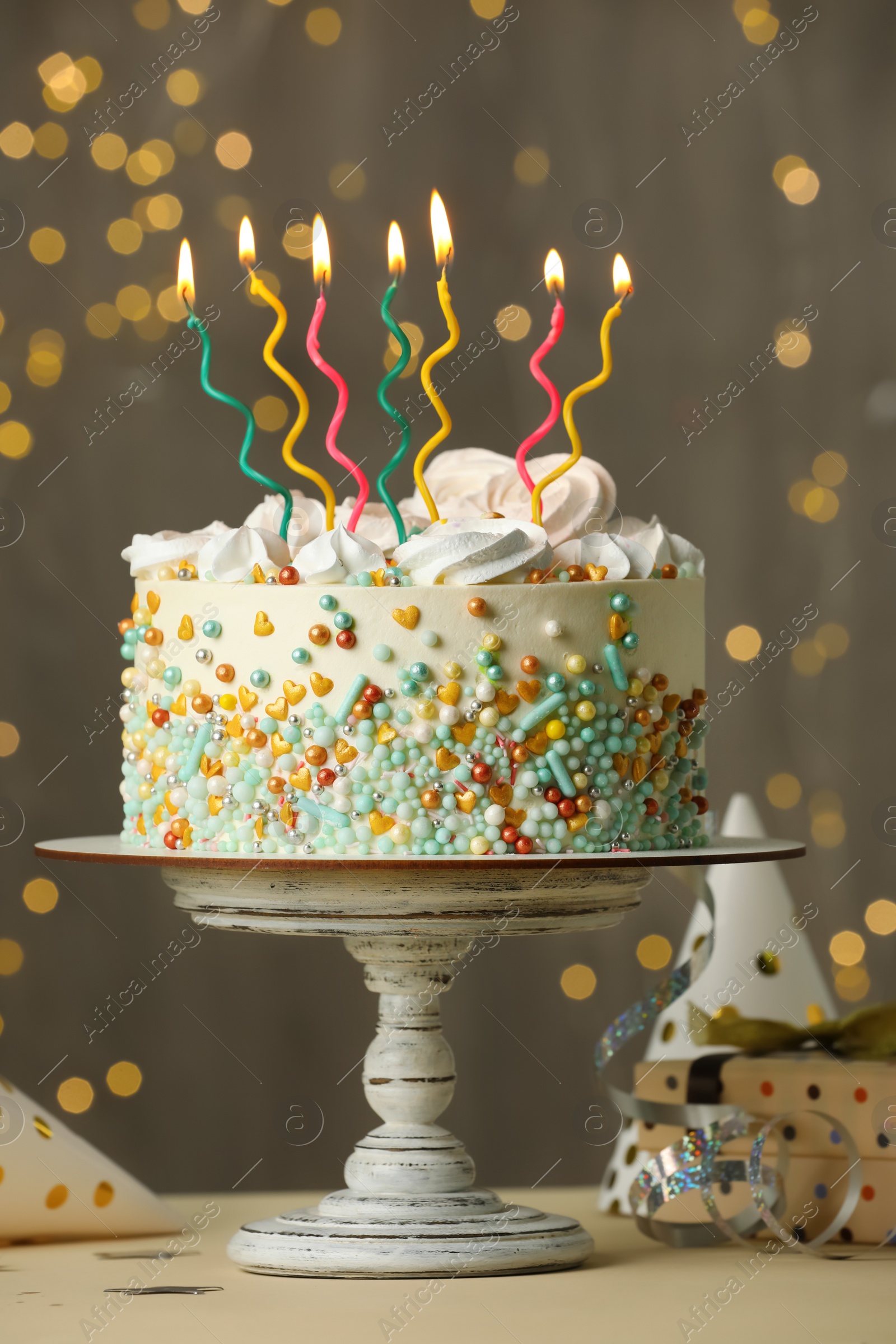 Photo of Beautiful birthday cake with burning candles and decor on white table