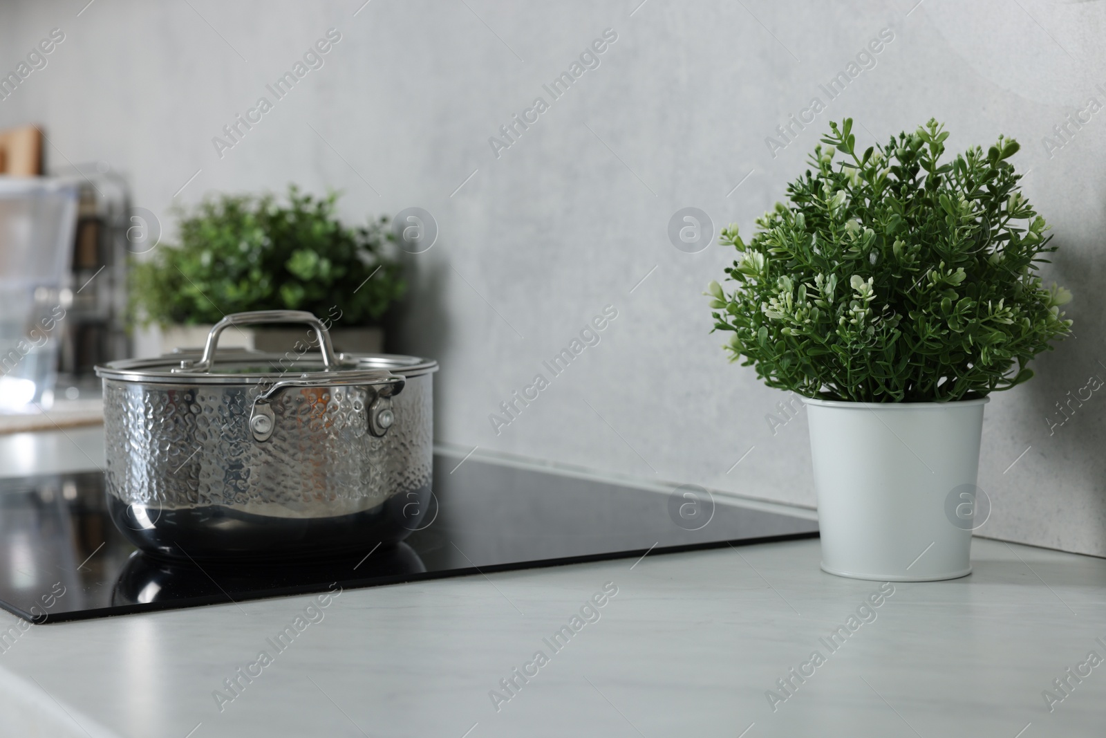 Photo of Potted artificial plants on white countertop in kitchen