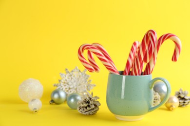 Photo of Candy canes and Christmas decor on yellow background, space for text