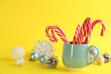 Candy canes and Christmas decor on yellow background, space for text