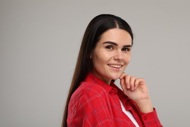 Young woman with clean teeth smiling on light grey background. Space for text