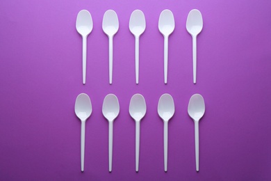 Plastic spoons on color background, top view. Picnic table setting