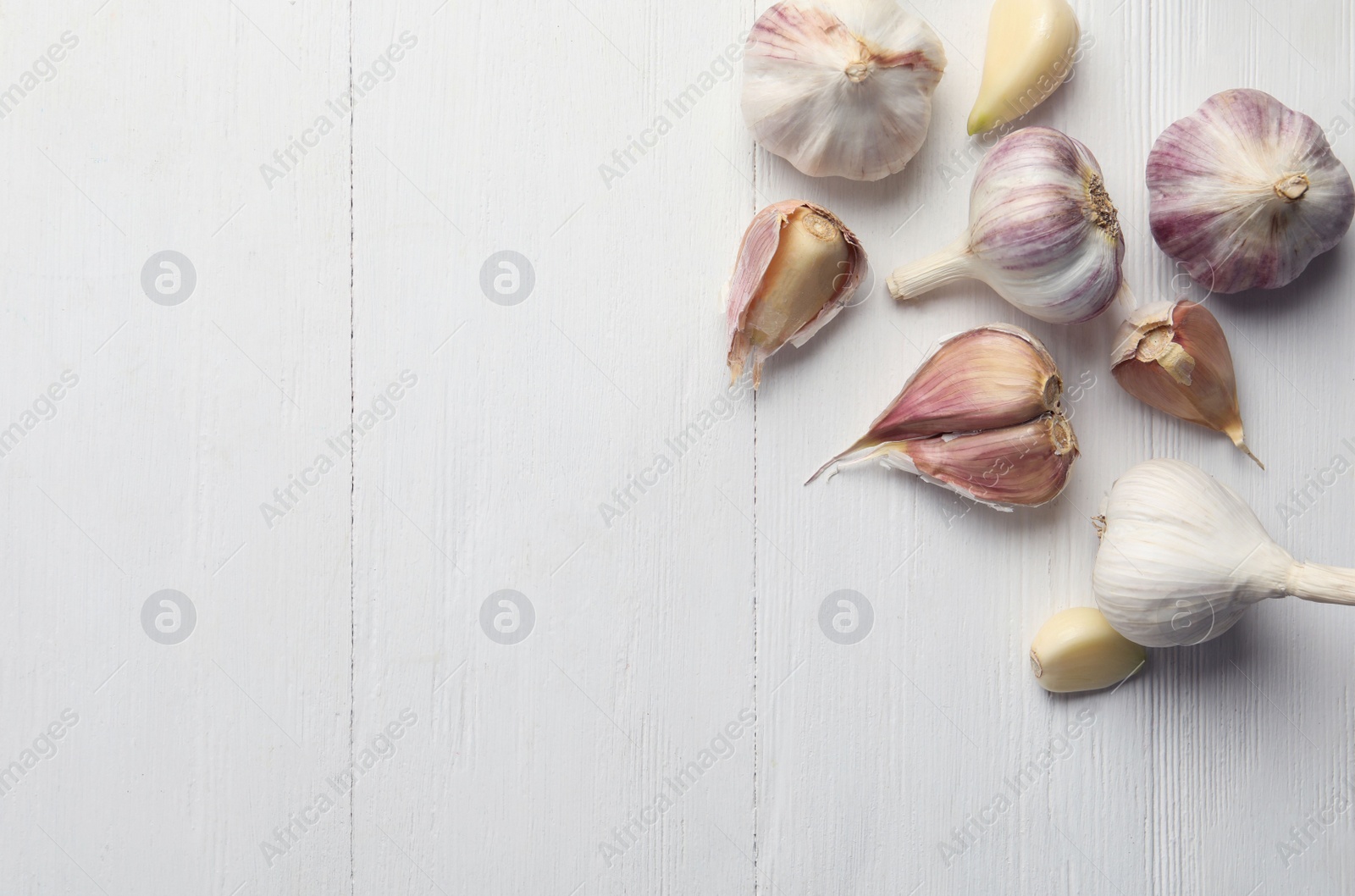 Photo of Fresh organic garlic on white wooden table, flat lay. Space for text