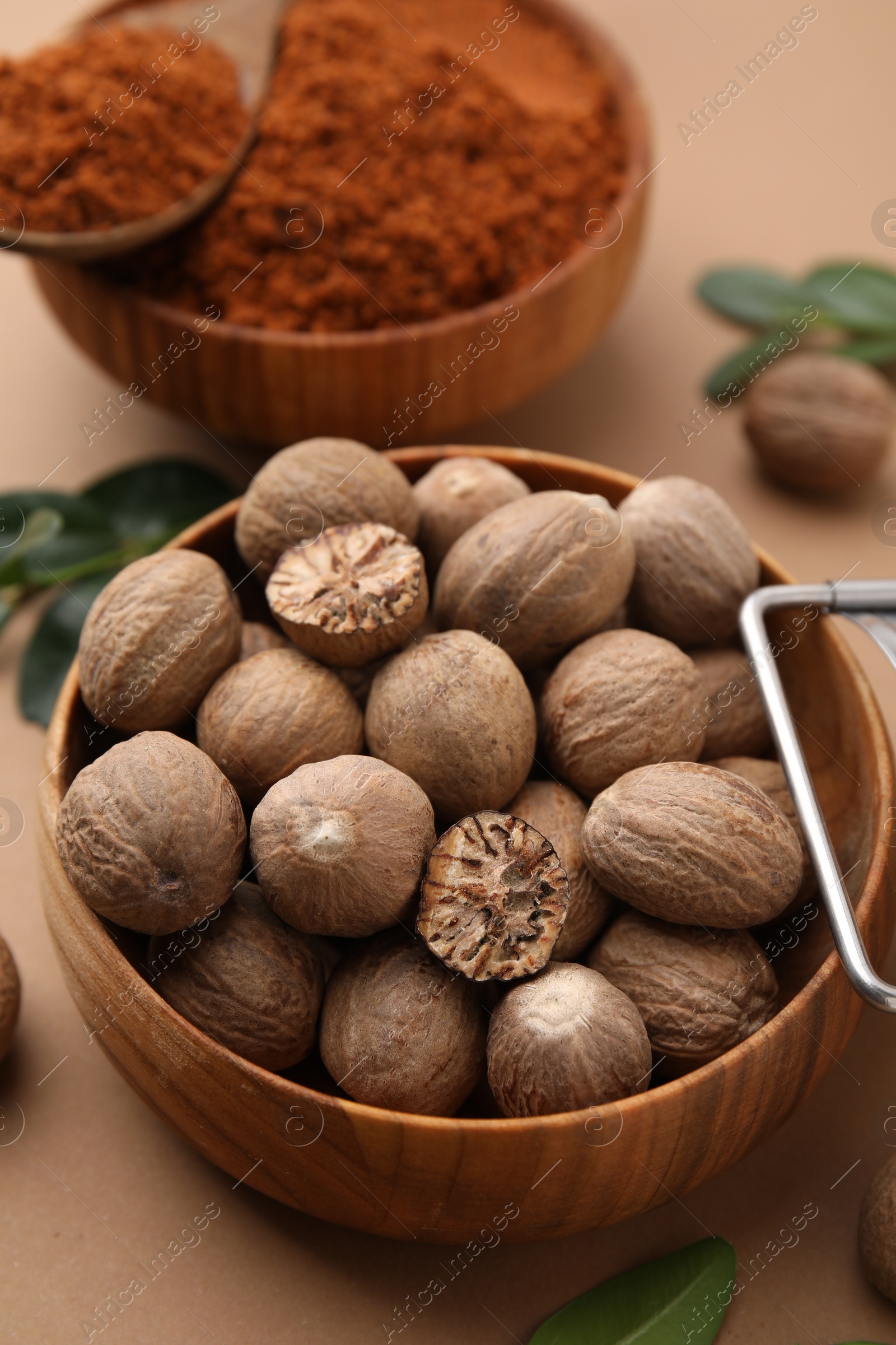 Photo of Nutmeg powder and seeds on light brown background