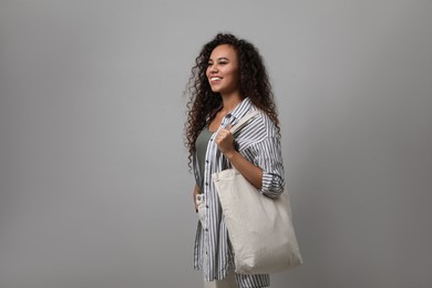 Happy African-American woman with eco bag on grey background. Space for text