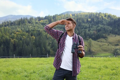 Photo of Man with backpack and binoculars in mountains