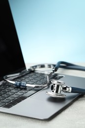 Photo of Stethoscope and modern laptop on grey table