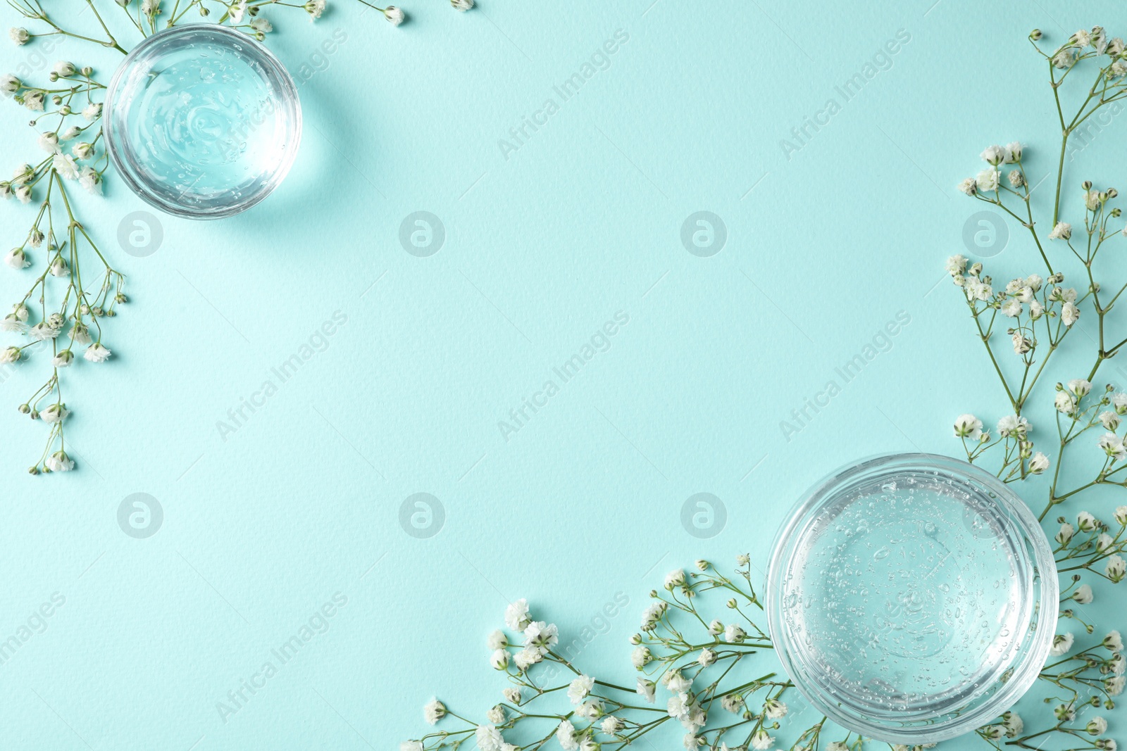 Photo of Flat lay composition with cosmetic gel and beautiful flowers on light blue background. Space for text