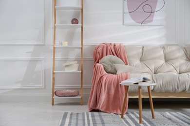 Modern living room interior with comfortable sofa and pink blanket