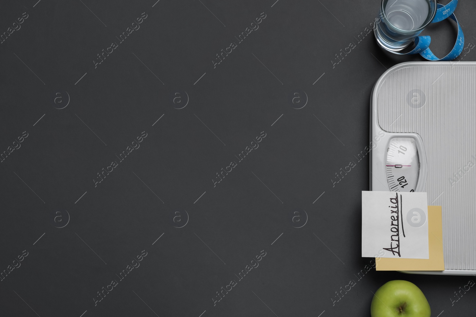 Photo of Flat lay composition with word Anorexia and scales on dark grey background. Space for text