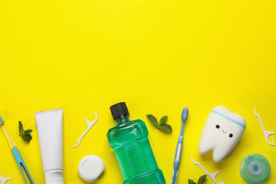 Photo of Flat lay composition with mouthwash and other oral hygiene products on yellow background. Space for text