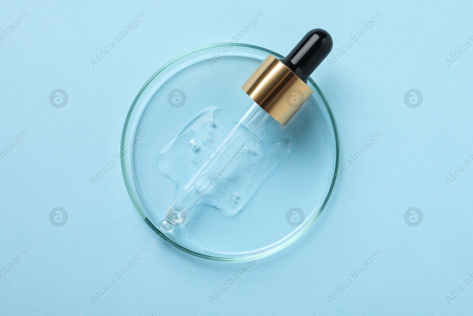 Photo of Petri dish with sample of cosmetic oil and pipette on light blue background, top view