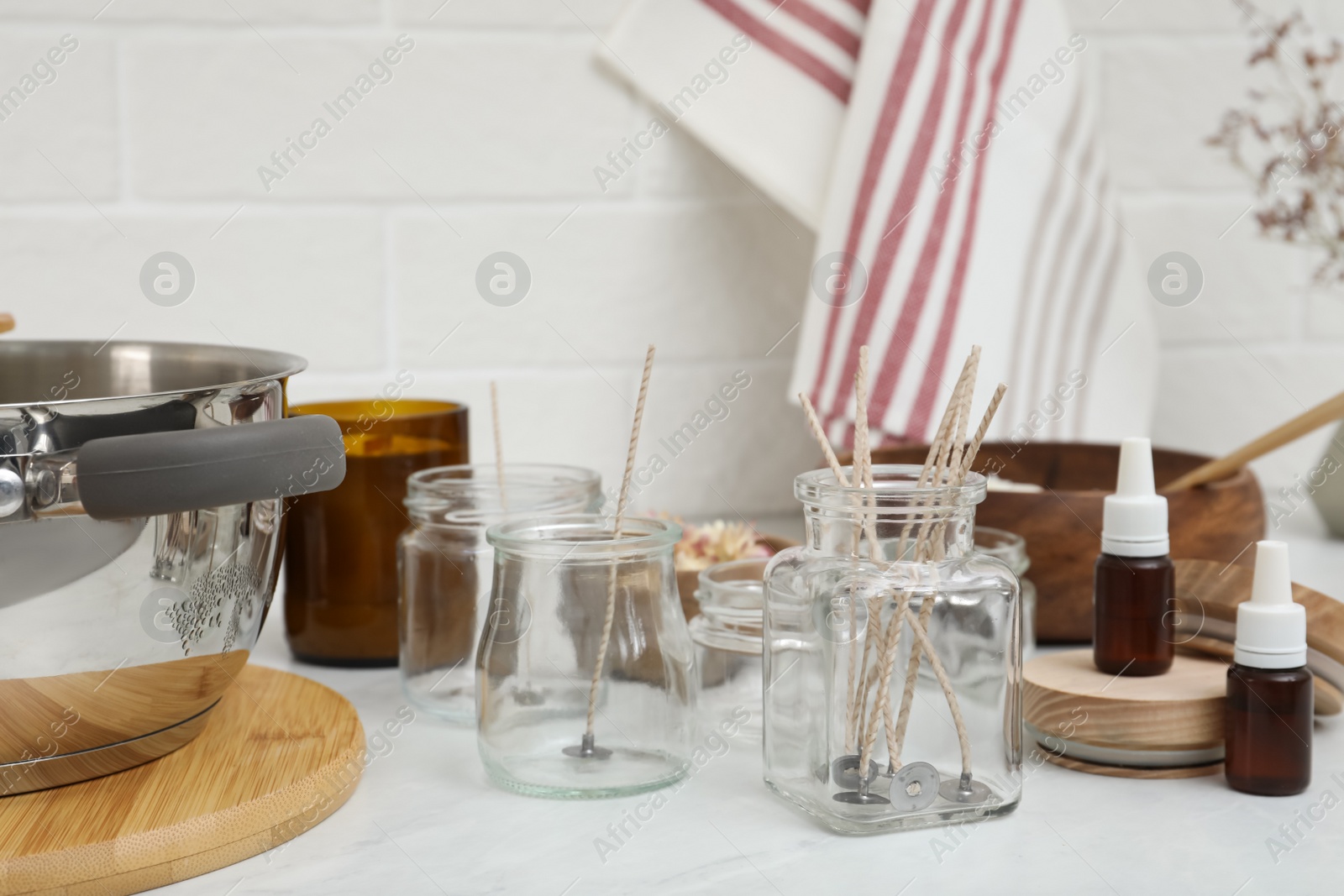 Photo of Glass jars with wicks on white kitchen table. Making homemade candles