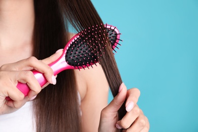 Woman with hair brush on color background, closeup. Space for text