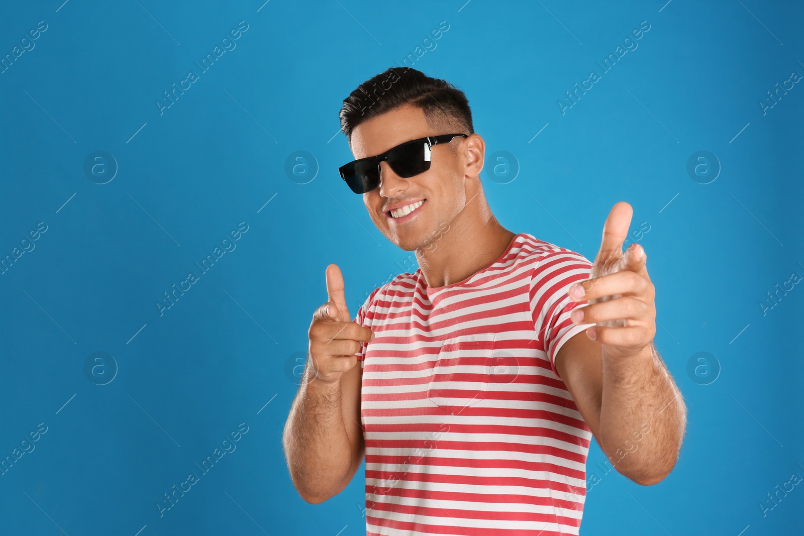 Photo of Handsome man wearing sunglasses on blue background