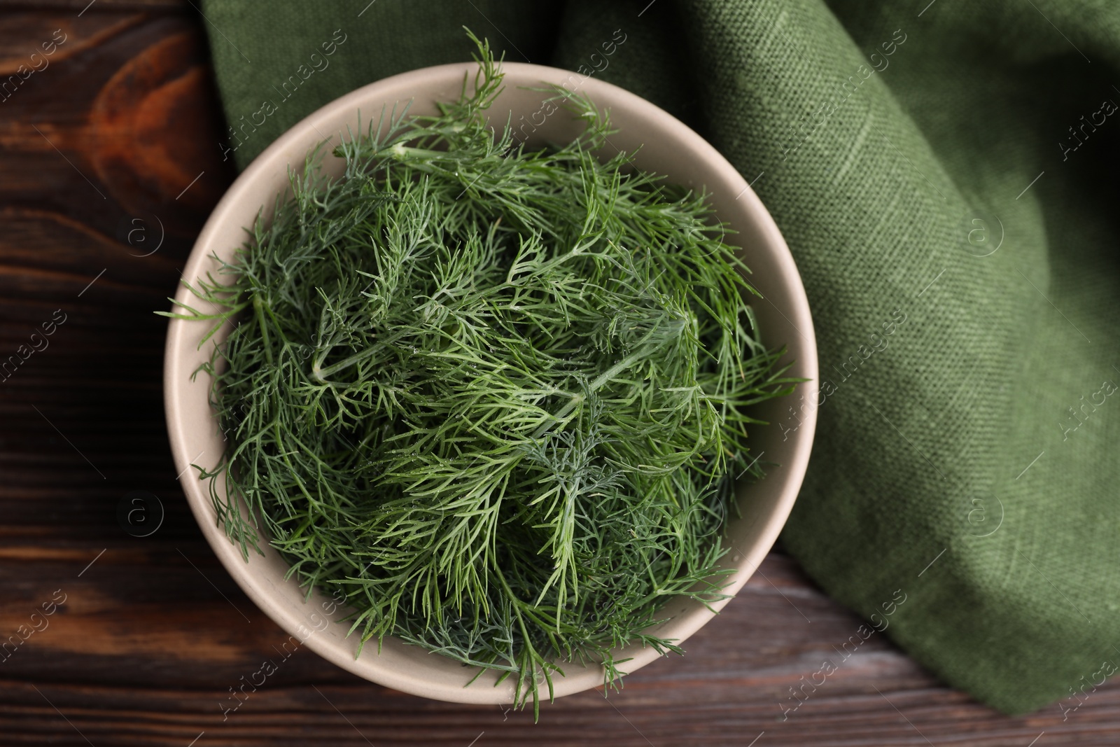 Photo of Bowl of fresh dill on wooden table, top view