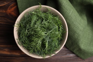 Bowl of fresh dill on wooden table, top view