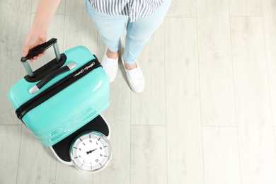 Photo of Woman weighing suitcase indoors, top view. Space for text